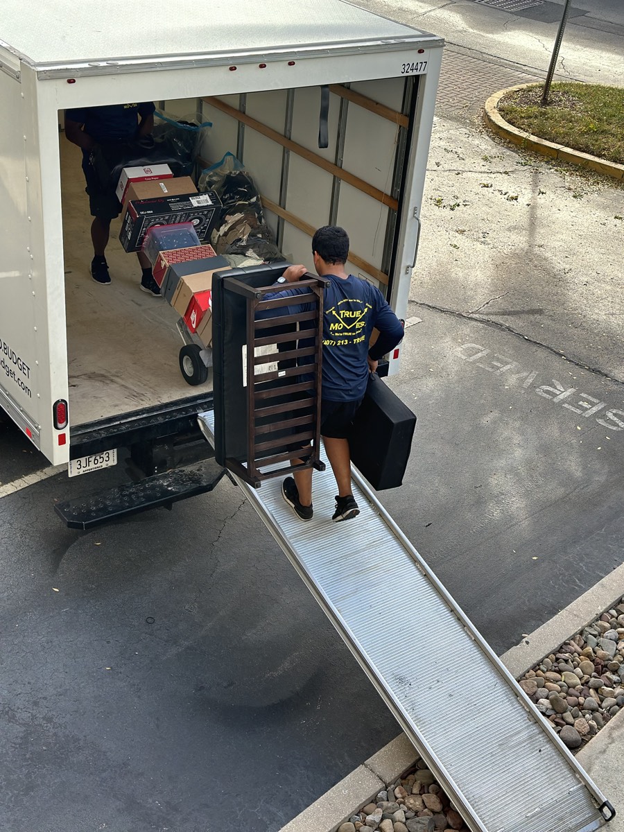 Mover bringing a crib down the truck ramp with care