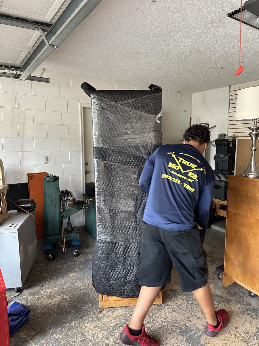 Mover protecting a large item with moving blankets